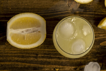 ripe sliced lemon and cold juice with ice and their reflection on a wet table