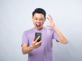 Young Asian man in a lavender t-shirt looking surprised and excited while waving at his smartphone....
