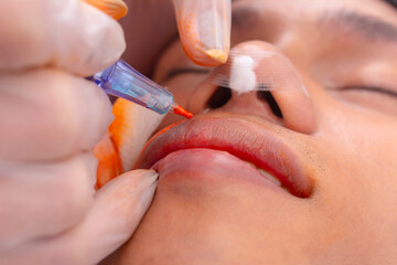 Closeup of Tattoo rotary pen in action for lip pigmentation or tint procedure for men. Gauze on...
