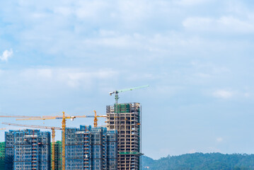 Construction crane of high rise building construction site with cloudy sky background. © torjrtrx