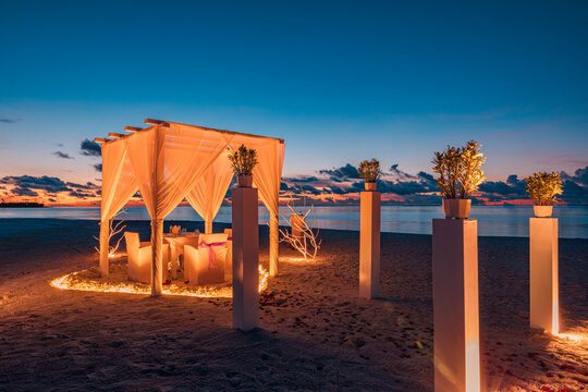 Romantic proposal sunset dinner. Candles white decoration pavilion, door close to sea sand beach. Love honeymoon anniversary dinner on tropical beach. Destination romance wedding, luxury couple travel