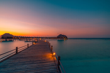 Obraz premium Amazing beach landscape. Beautiful Maldives sunset seascape view. Horizon colorful sea sky clouds, over water villa pier pathway. Tranquil island lagoon, tourism travel background. Exotic vacation