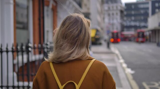 Cinematic dramatic video of a mysterious woman turning her back on the camera and walking away in a London street in slow motion