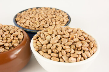 Tres tigelas de cores diferentes cheias de feijao cru, prontos para serem cozidos e transformados em uma deliciosa e nutritiva refeicao caseira.