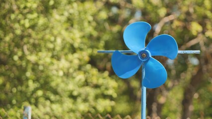 A blue vane weathervane spins in the wind in the summer.