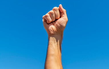 Strong fist against a clear blue sky.