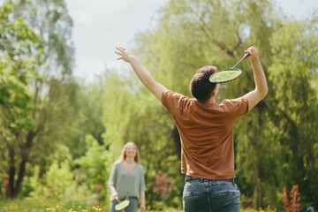 Fototapeta premium A young couple is playing badminton on a lawn in a park.