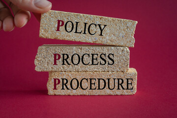 Brick blocks with words 'Policy, process, procedure' on beautiful wooden table, blue background....