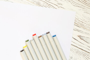 set of color markers laying on white sheet of paper
