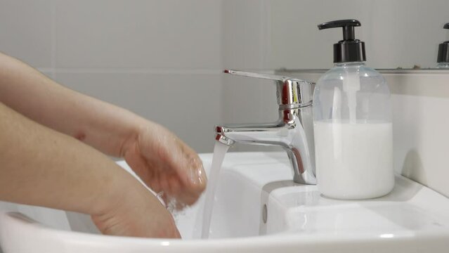 A close up of a woman washing her hands with soap and turning off the tap to save water in the bathroom.Water saving concept
