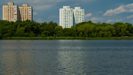 Multi-storey panel buildings, overlooking a large pond and dense trees