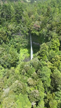 Aerial video of Salto El Leon waterfall flowing over a rocky pool, Pucon, Chile