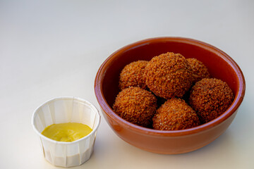 Bitterballen, Dutch meat-based snack in brown bowl served with yellow mustard on the tabel background, Typically containing a mixture of beef or veal, Bitterball are one of Holland's favorite snacks.