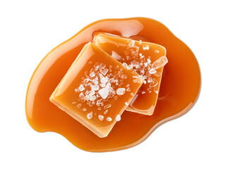 Two salty or salted caramel candy cubes topped with caramel sauce and sea salt on white background