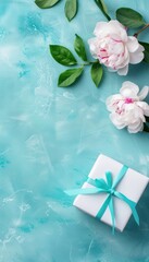 A white gift box with a blue ribbon sits on a blue background, surrounded by delicate pink peonies.  A perfect background for a greeting card.