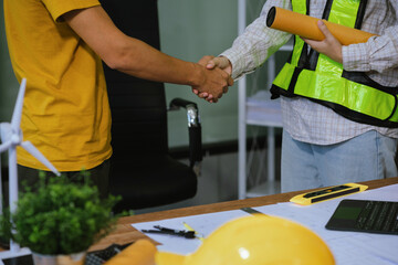construction worker wearing a protective helmet and vest is holding his colleague's hand while working at the job site.