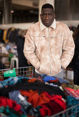 Guy from South Africa sells used clothes at a flea market.