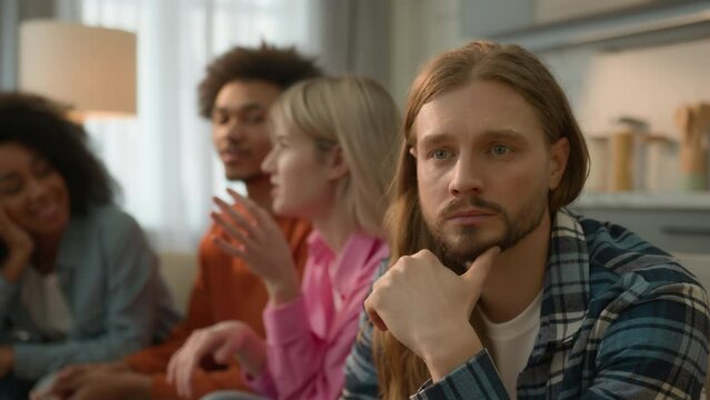 Caucasian sad pensive thinking troubled problem frustrated man guy introvert at home separated ignoring multiracial African multiethnic friends women men laughing talking antisocial outsider male