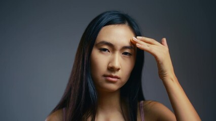 Sad Asian woman displeased with face skin imperfections, loss of shine, beauty