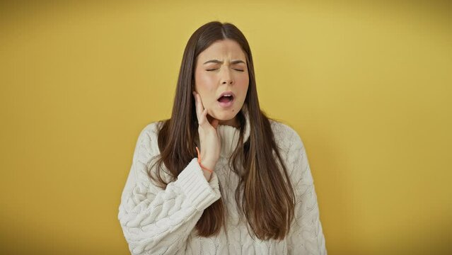 Hispanic young beauty in sweater, aching tooth pain visible on her face. standing isolated over yellow, hand touching mouth. dentist's nightmare!