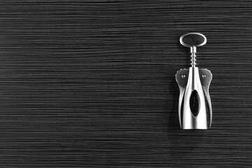 One wing corkscrew on black wooden table, top view. Space for text