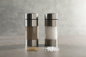 Salt and pepper shakers on grey textured table, closeup