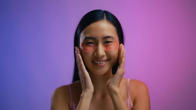Beautiful Asian woman applying under eye patches, beauty routine, cosmetology