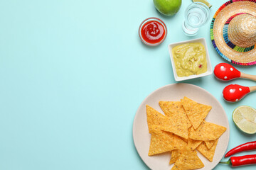Flat lay composition with nachos chips and Mexican sombrero hat on light blue background, space for text