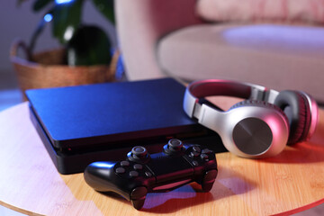 Video game console, wireless controller and headphones on wooden table indoors © New Africa