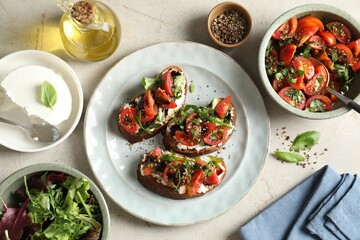 Delicious bruschettas with ricotta cheese, tomatoes, arugula, salad and peppercorns on light table, flat lay