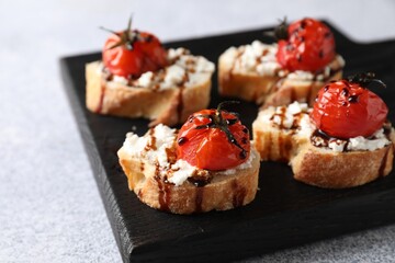 Bruschettas with ricotta cheese, tomatoes and balsamic sauce on grey table, closeup
