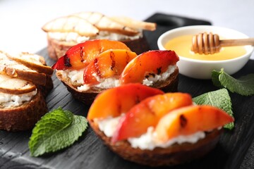 Delicious bruschettas with ricotta cheese and honey on light grey table, closeup