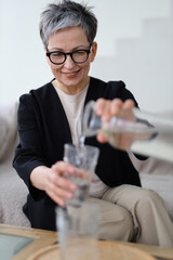 Happy woman drinking water at home, embracing a healthy lifestyle and staying hydrated.