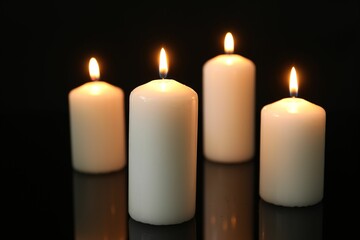 Many burning candles on mirror surface against black background