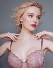 Beautiful blonde woman with a perfect body in lingerie with petals in the background. Studio spring tender concept.