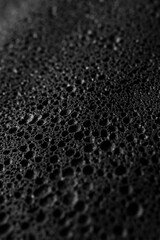 Close-up view of water droplets on a black surface, suitable for use in science or technology contexts