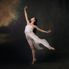 Ballet dancer's elegant pose with her dress flowing on wind against vintage studio background....