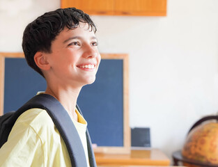 preteen boy happy and excited about going back to school, with a backpack and globe in the background.