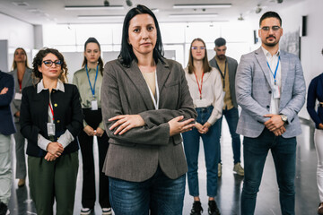 Portrait of  Hispanic woman CEO standing  with her hands crossed in front of her colleagues.