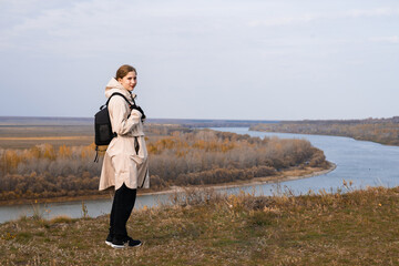 A young girl stands on a high bank and looks at the beautiful nature