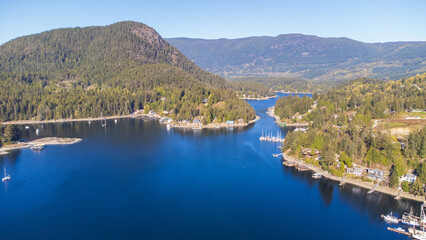 Gerrans Bay on a sunny morning. Looking up a small inlet with mountains and forest surrounding the shoreline. Boats and homes dot the landscape.