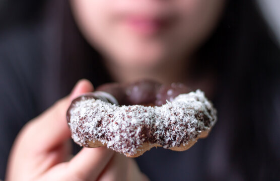 Close up, Woman eating chocolate donu blurred background