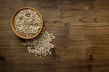 Raw sunflower seeds in wooden bowl, top view