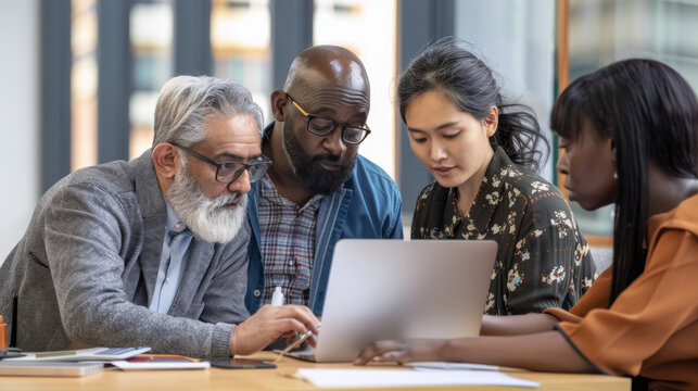 A focused team of professionals collaborates around a laptop, demonstrating teamwork and dedication in a workplace setting.