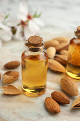 Almond oil in bottle and nuts on color marble table, closeup