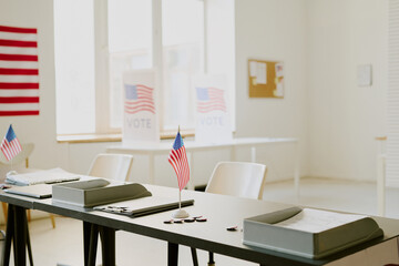 No people shot of part of polling station interior with flags, ballot papers, pens and pins on table, copy space