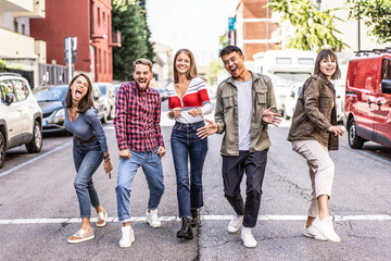 Group of friends having fun on the street. Five diverse young adults enjoying a day out and expressing happiness. Millennials showing friendship and joy.