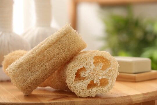 Loofah sponges on wooden table indoors, closeup