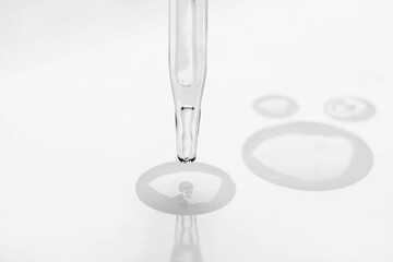 Glass pipette and transparent liquid on white background, closeup