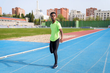 Fototapeta premium A african man in a green shirt is standing on a track